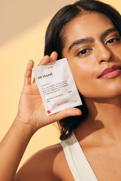 A close-up of a model holding a sustainable supplement sachet to bridge the gap between brand transparency and the end-user.